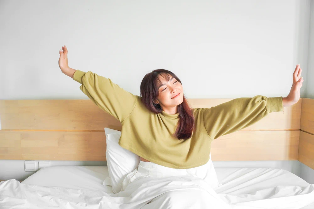 Happy woman waking up and stretching in bed