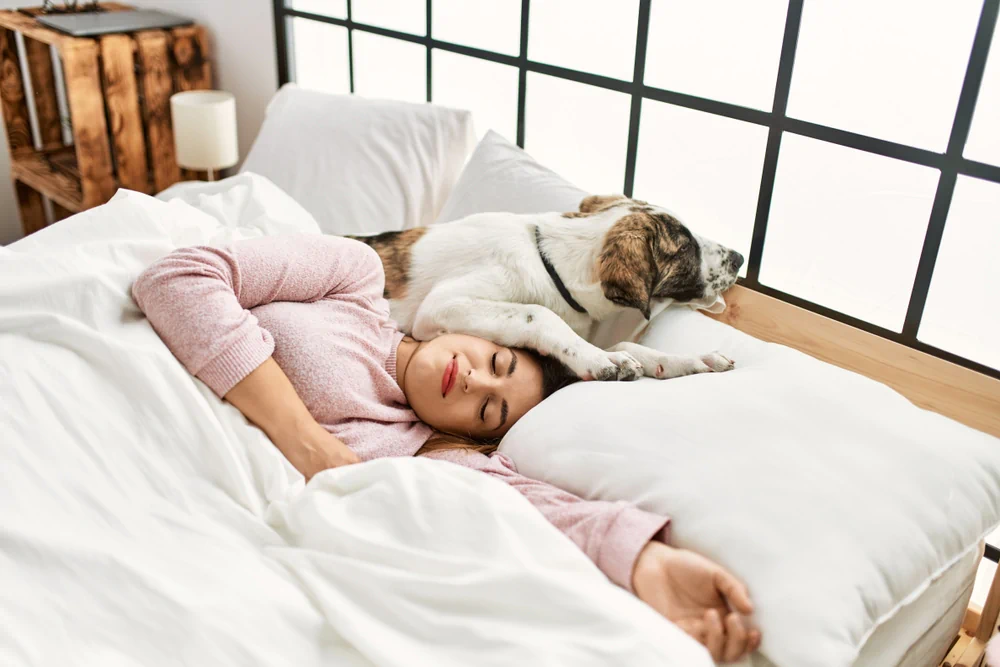 Woman sleeping in bed with her dog