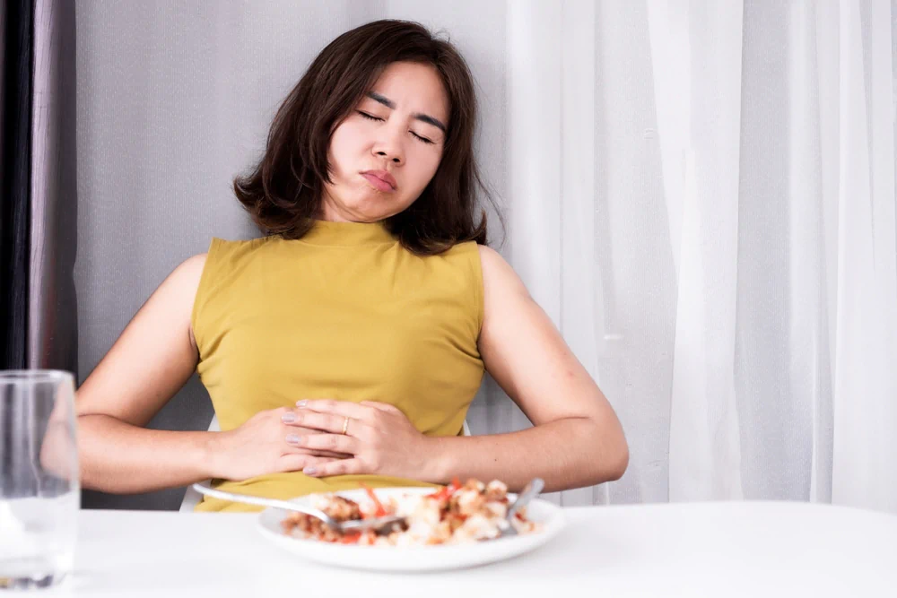 Woman with her eyes closed, feeling tired after eating a large meal