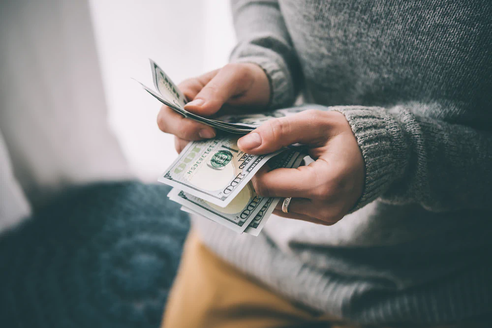 Person counting hundred dollar bills