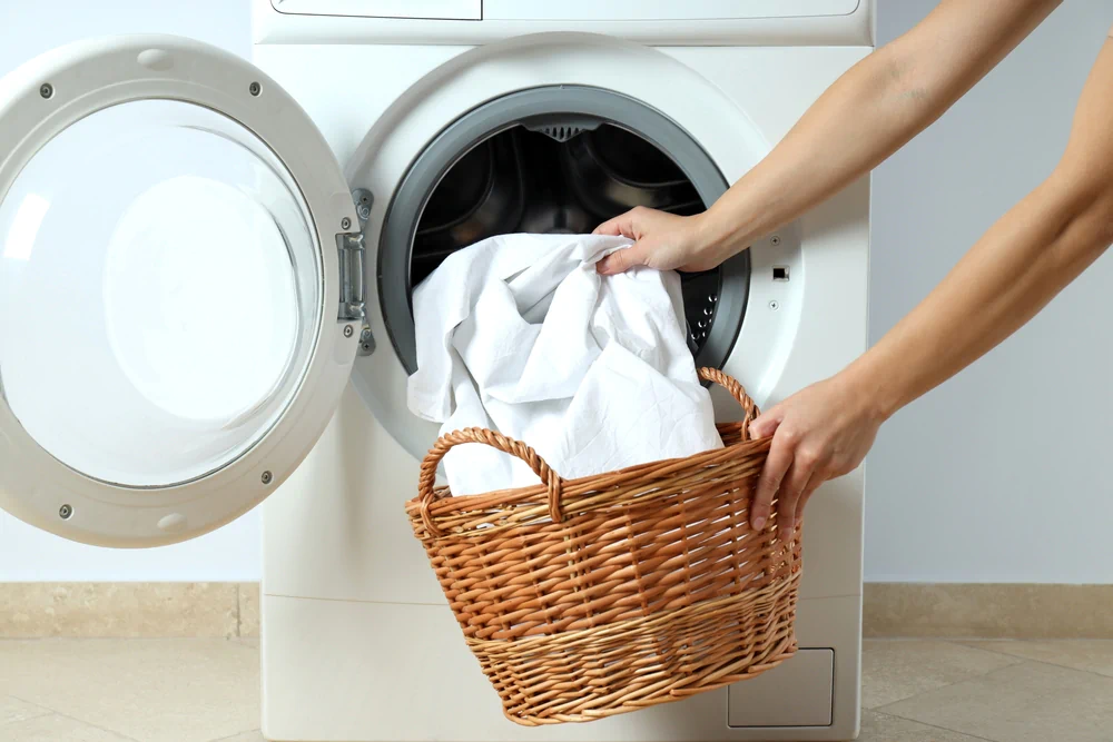 Someone pulling their mattress protector out of the washing machine