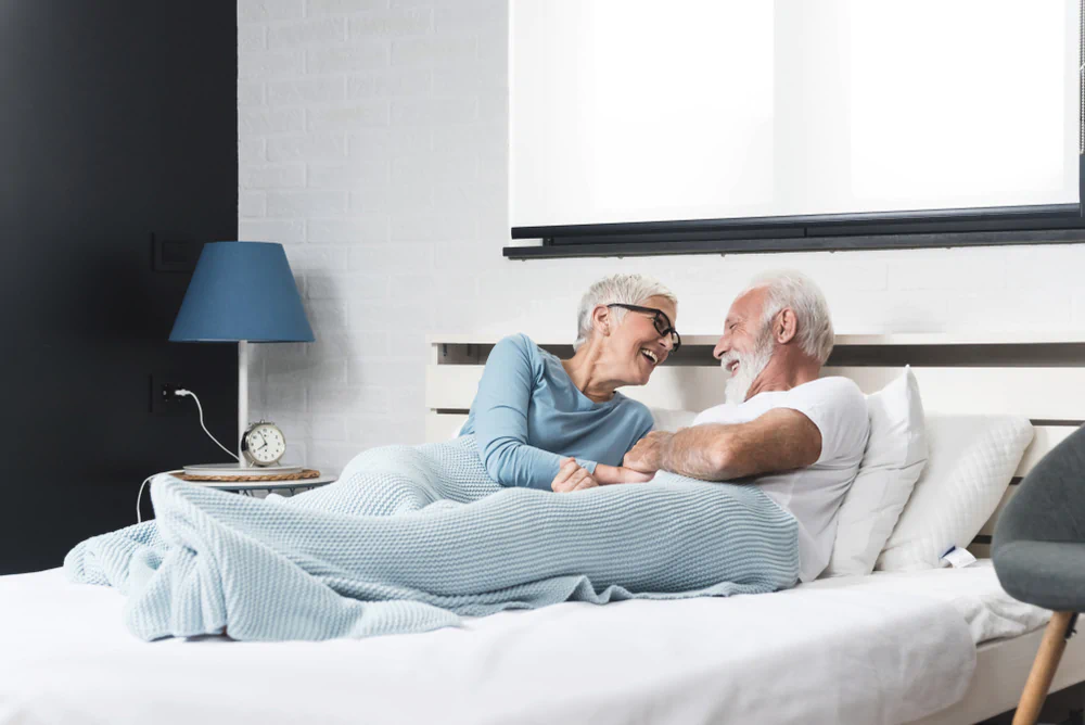 Elderly couple laughing on a mattress