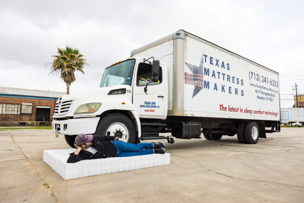 Noah from Texas Mattress Makers lying on the Quantum™ Coil component next to truck