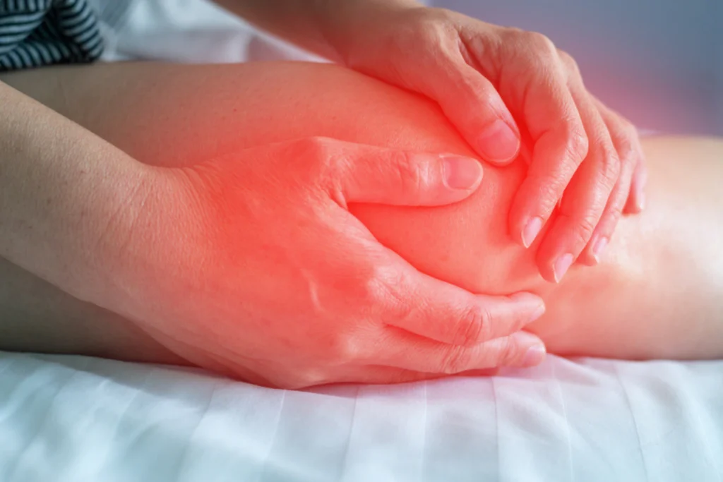 Hands cupping a hurt knee highlighted in red